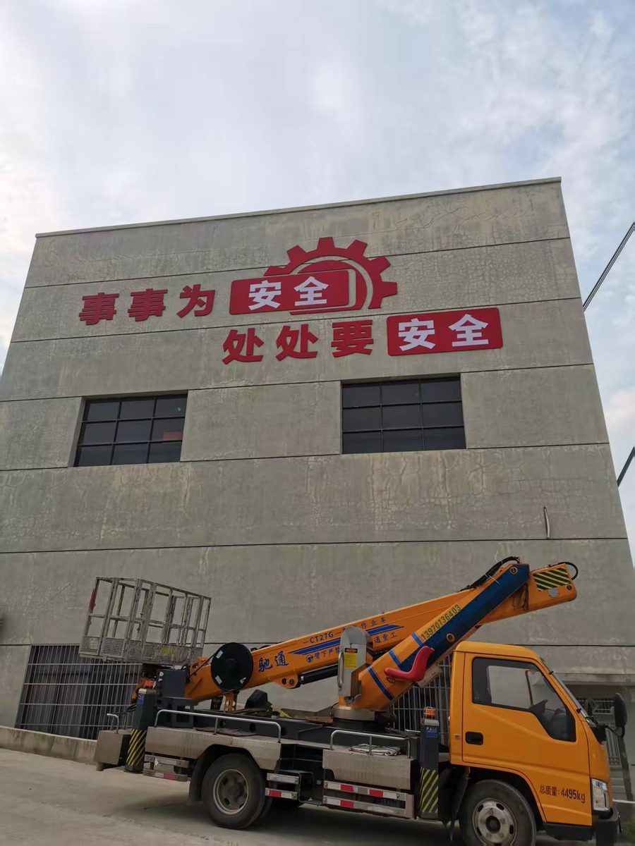 灰白墙面上的安全标语大字，是现场弹线定位后一个字一个字装上去的。